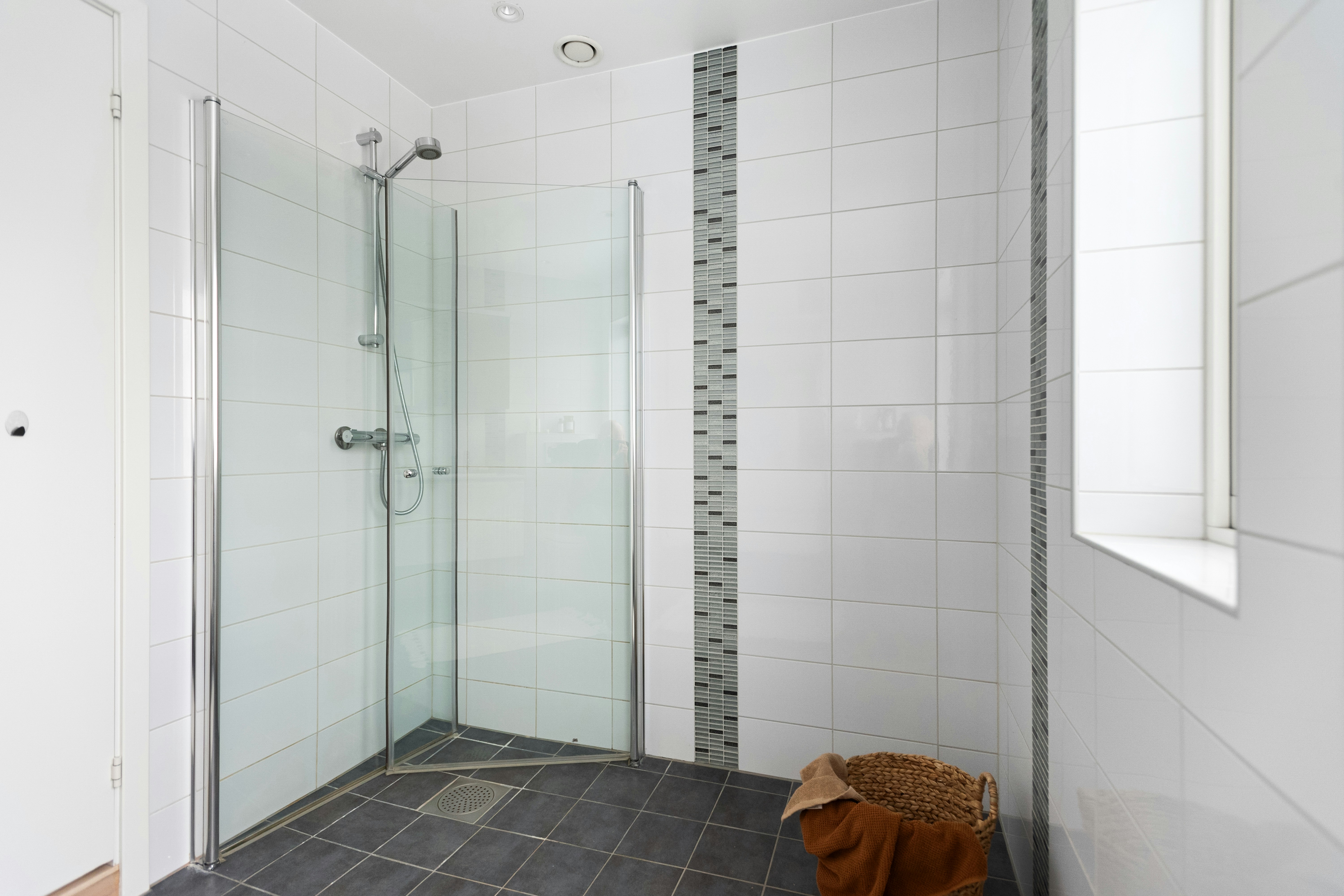 A bathroom with a walk in shower next to a window